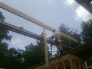 Carpenter setting a ridge beam over a new addition frame — Ice Dam Removal by Roofing Brothers in Winner