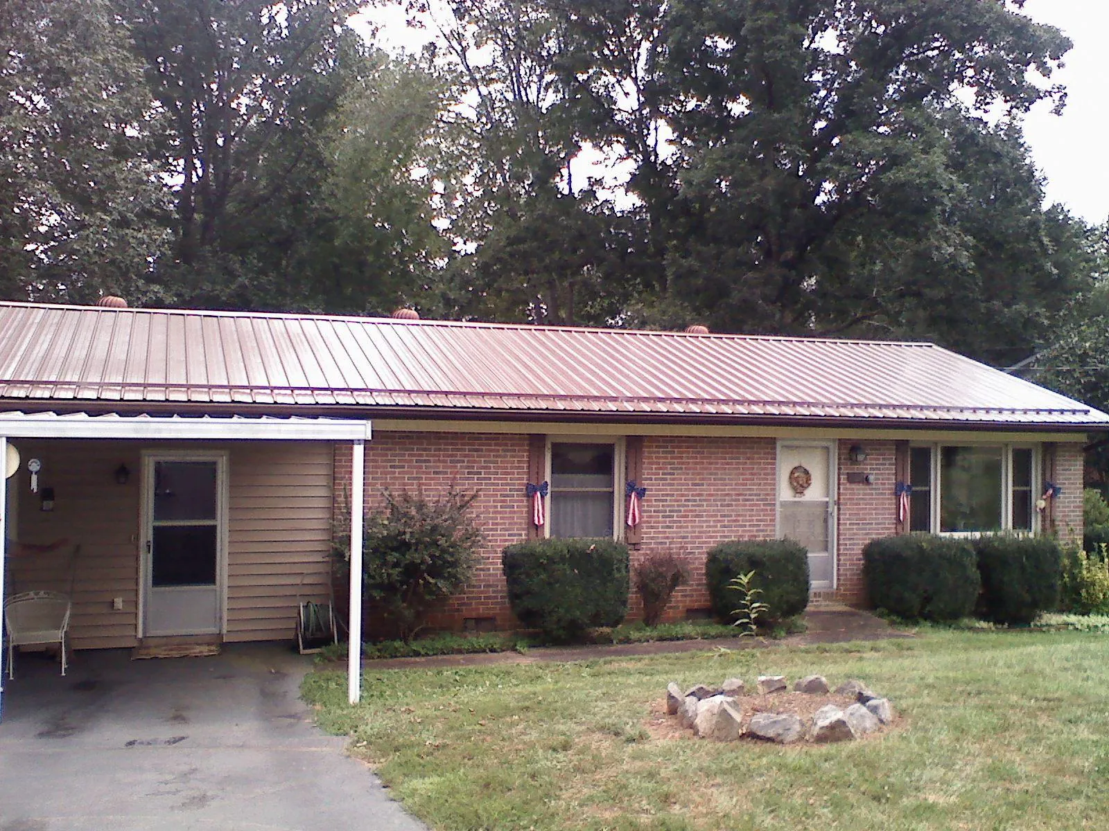 Bronze metal roof and carport on a brick ranch home — Roof Repair work by our crew in Winner