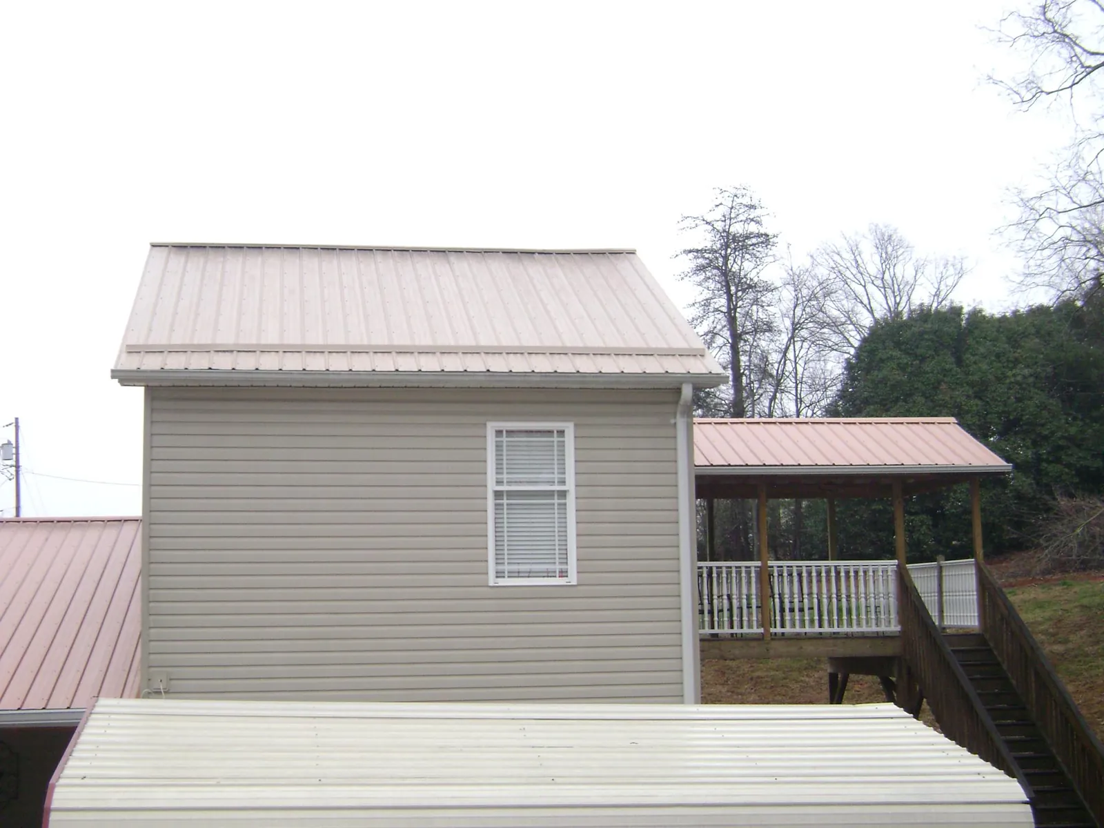 Tan metal roofs on a two story addition and attached porch, from a Roof Replacement job in Winner
