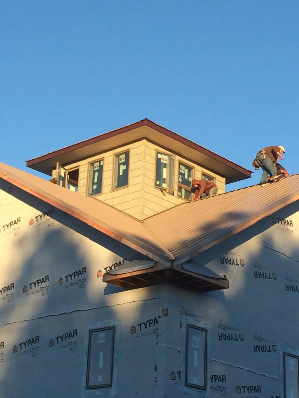Roofers working around a rooftop cupola on a new metal roof at sunset — Roof Waterproofing in Winner by Roofing Brothers